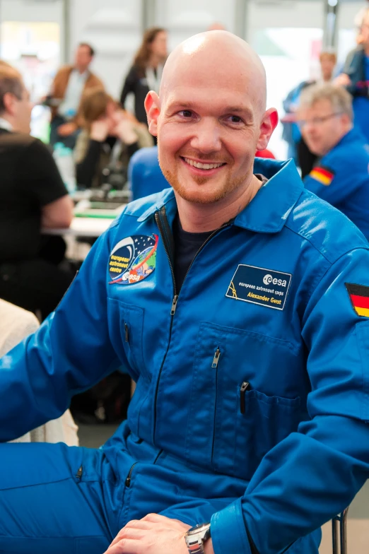 a male in a blue spacesuit sits on a chair