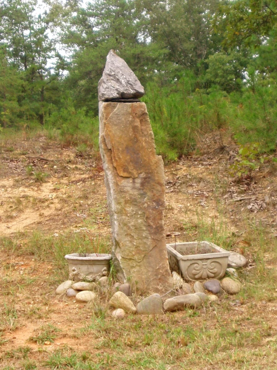 large rock with some pots near it on the ground