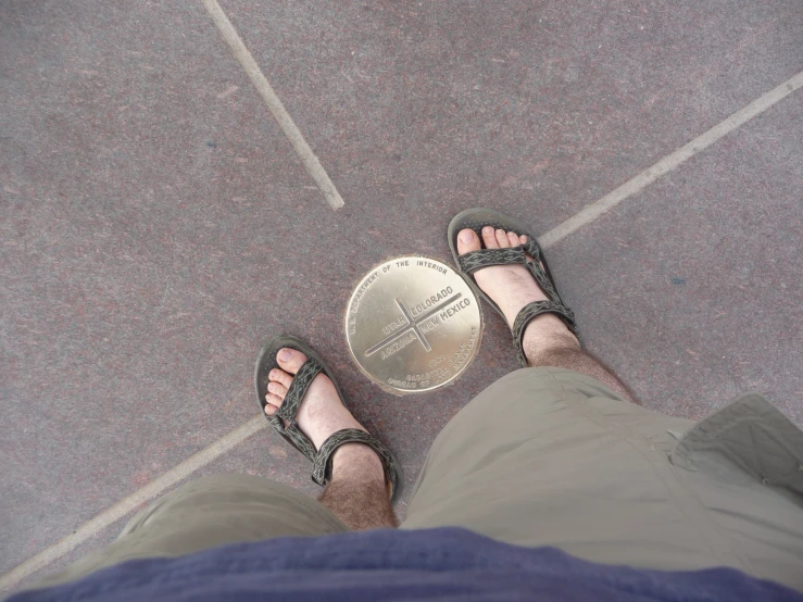 a person's feet with sandals and a medal on them