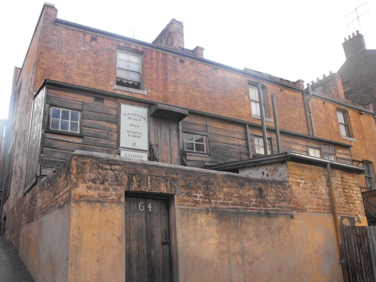 an old brown building is next to a small brick building