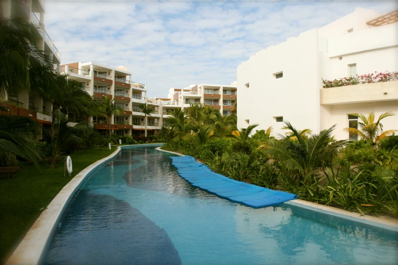 an outdoor swimming pool with a very long slide and some trees