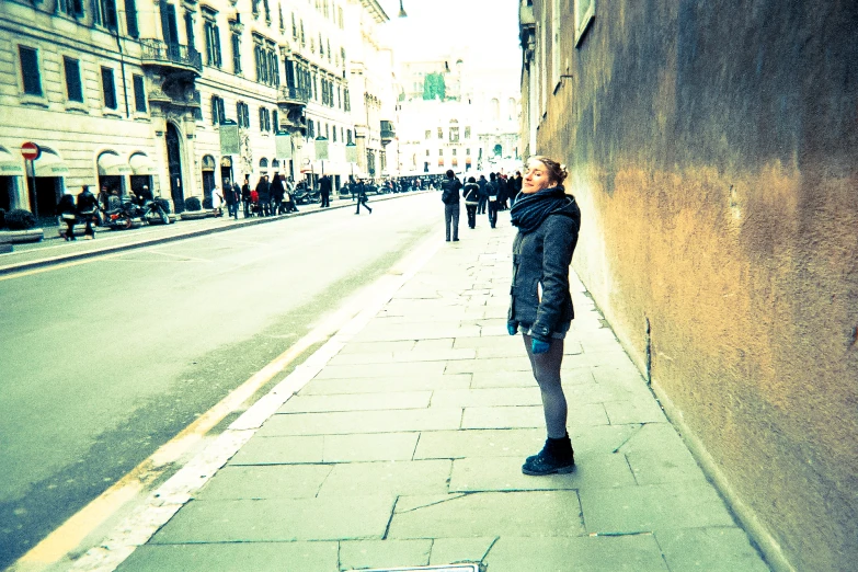 a woman standing on a street corner looking at the sidewalk