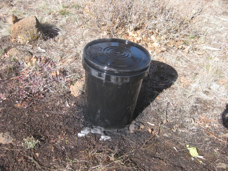 a black trash can is in the ground
