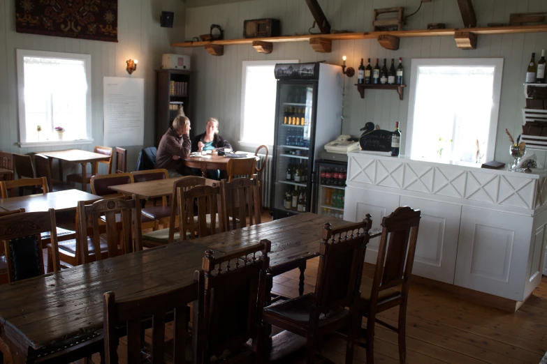 a couple of ladies are sitting at a table in a small restaurant