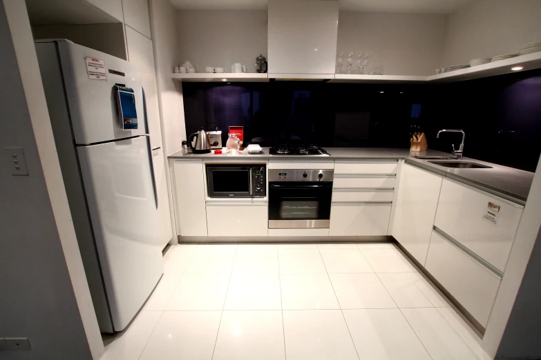 an empty kitchen with white cabinets and a fridge