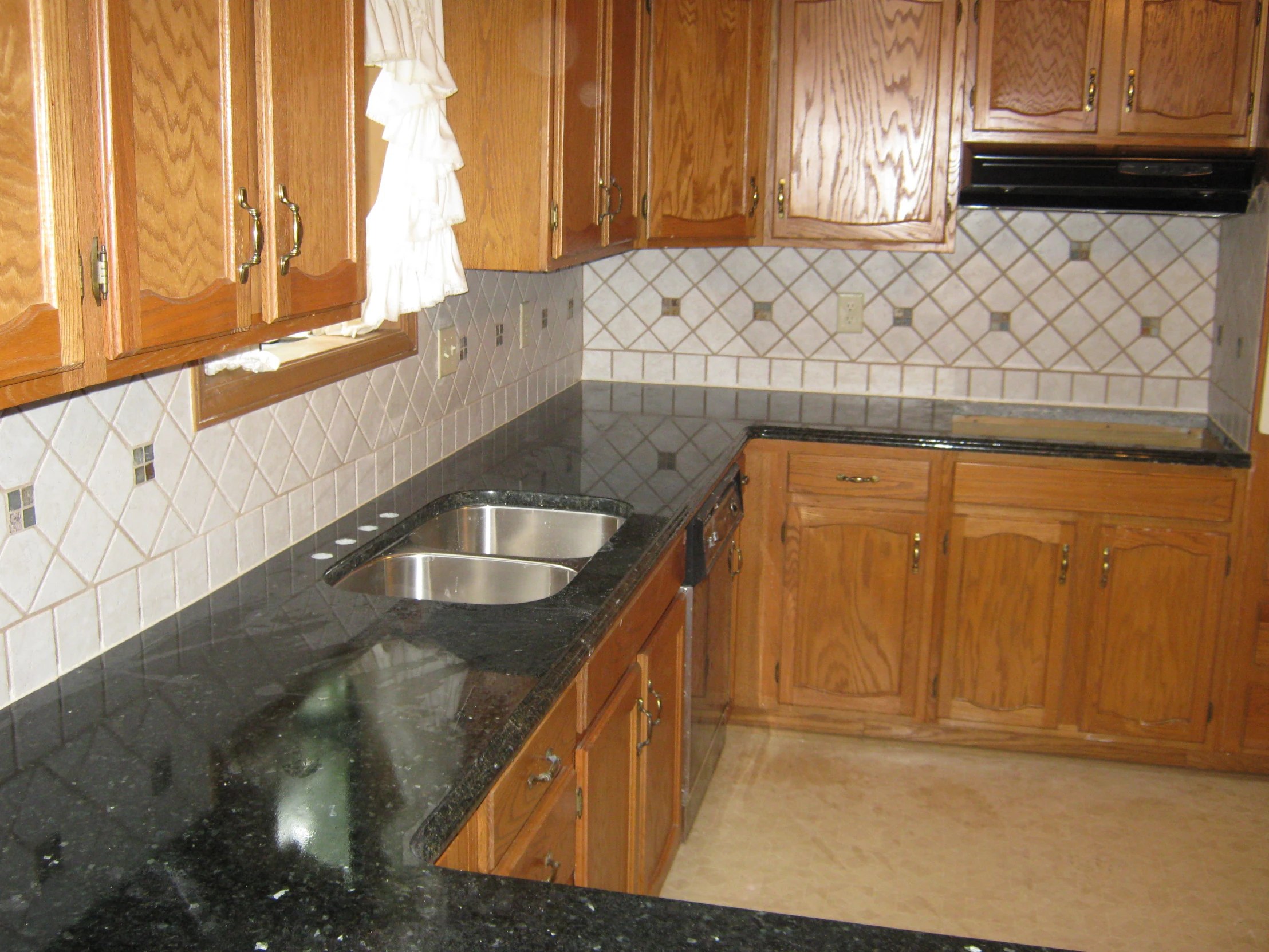 a very nice looking kitchen with wood cabinets and black marble counter tops