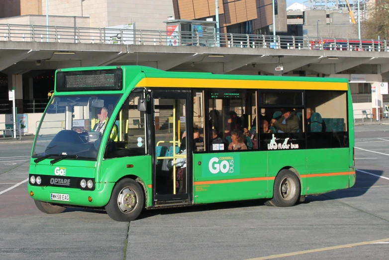 a green bus with passengers on the inside of it