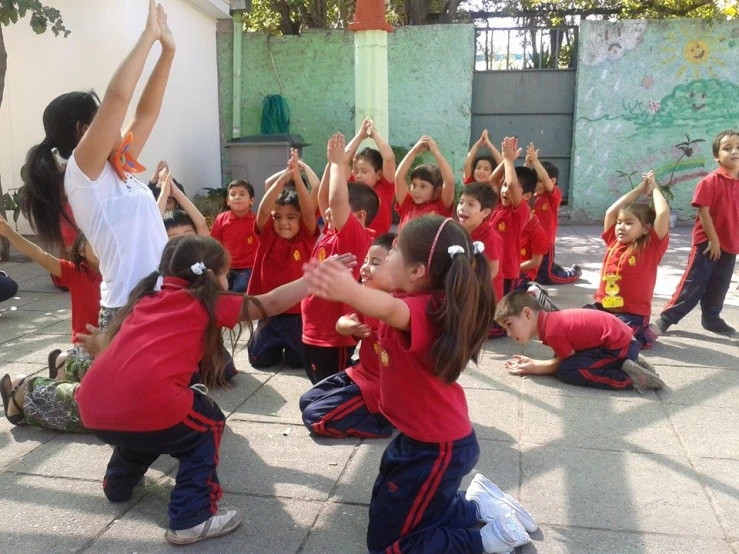 children in red shirts are doing exercises in a courtyard