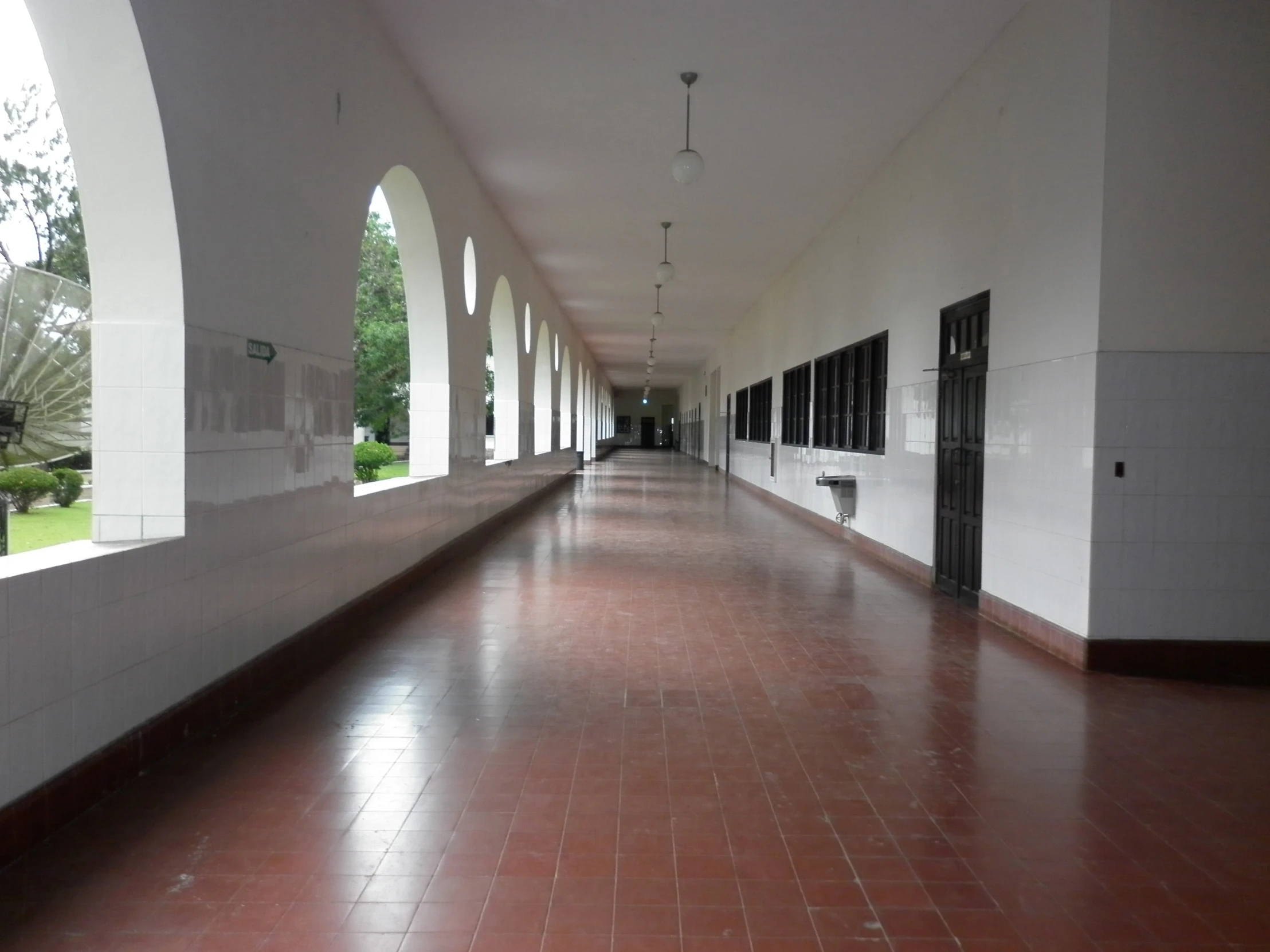 a long walkway lined with white arches between two buildings