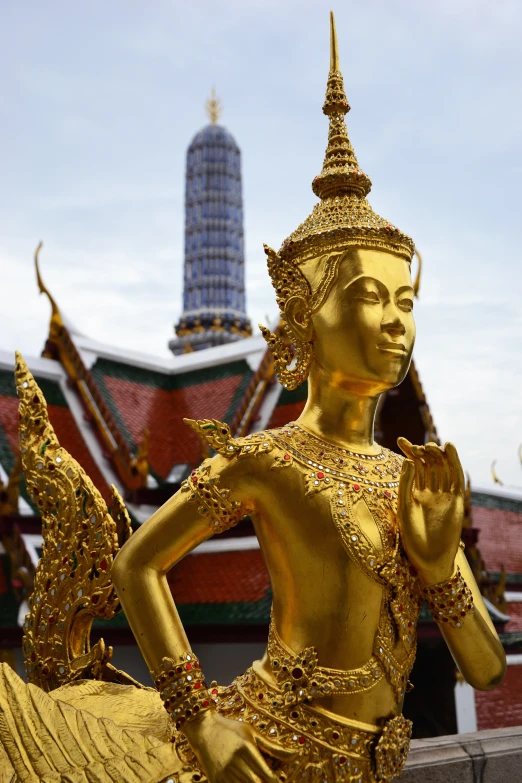 an oriental looking golden statue in front of a pagoda