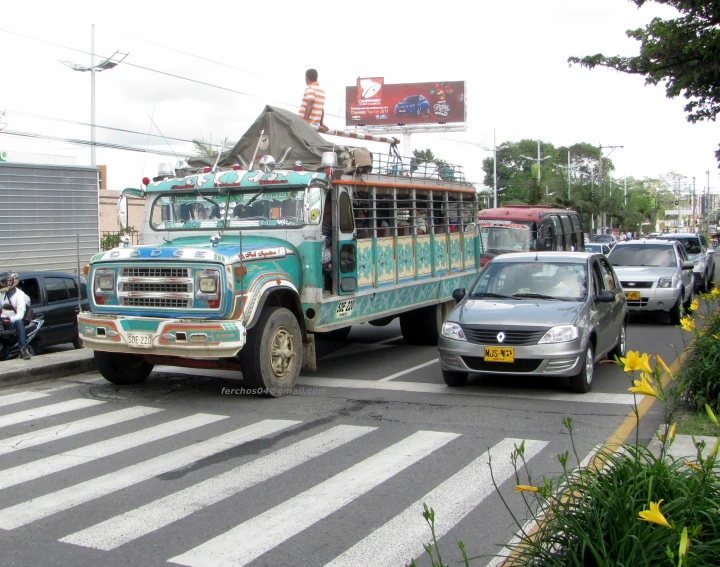 a large vehicle in traffic with people riding on the front