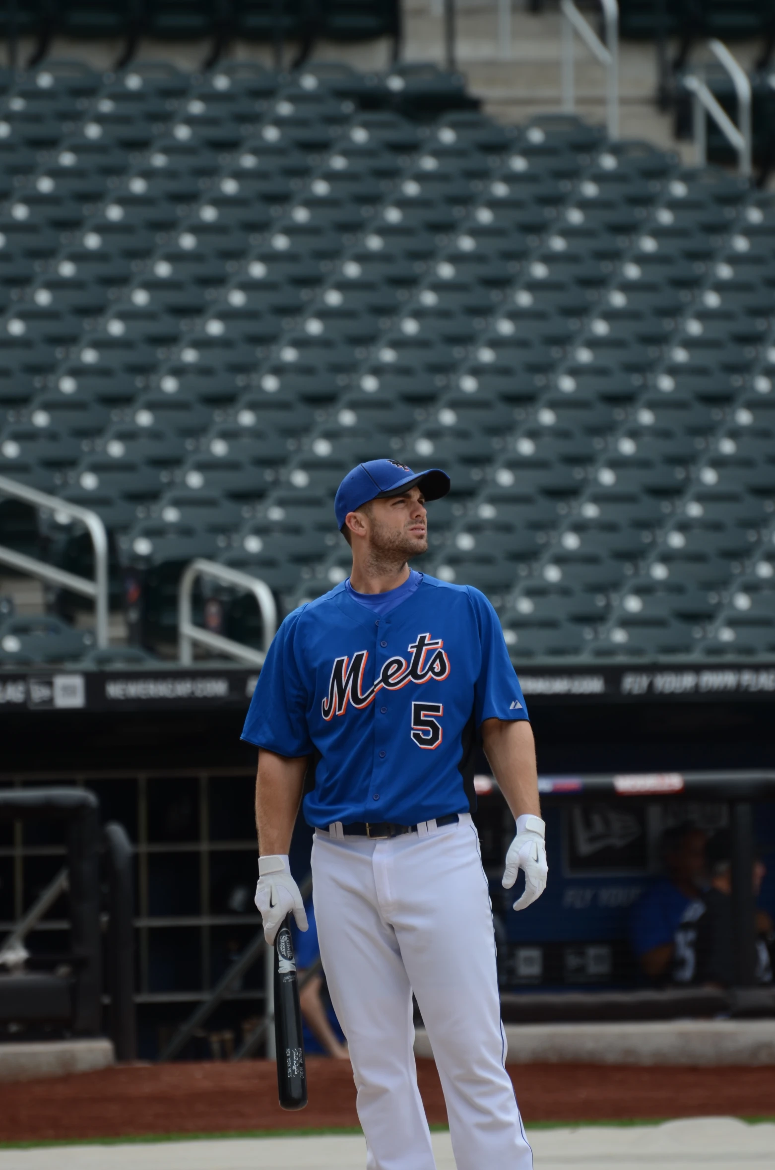 baseball player in blue jersey and white pants holding his bat