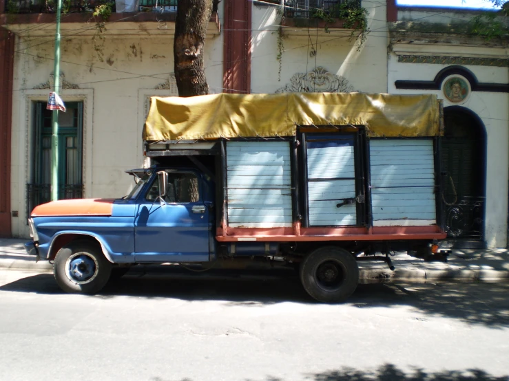 an old truck is painted blue with a yellow cover