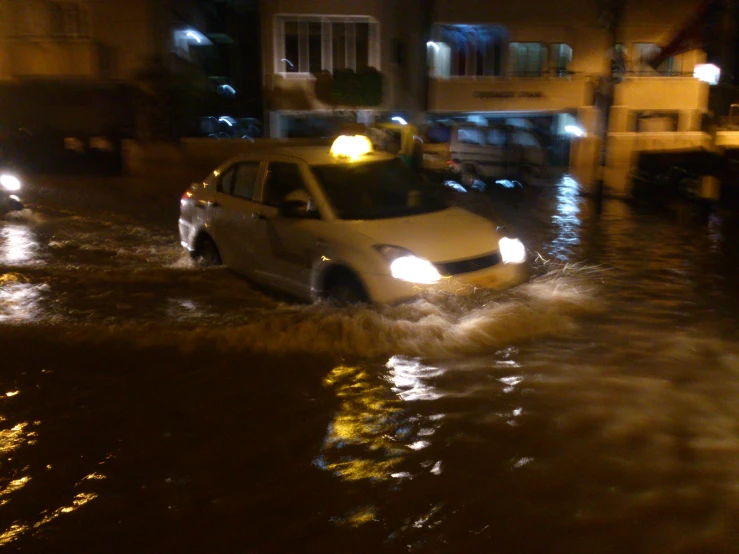 an suv drives through flood water in front of a building