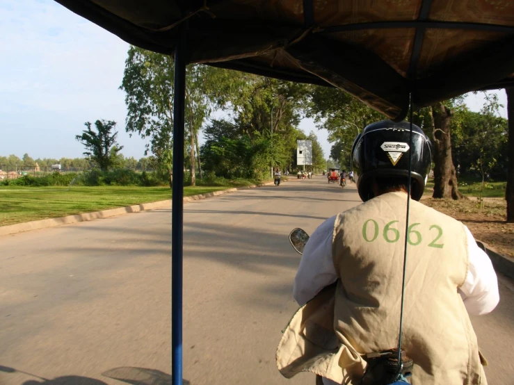 the back view of the person in the helmet and jacket on a motor scooter