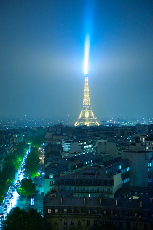 a city skyline, with some lights and a spire at night