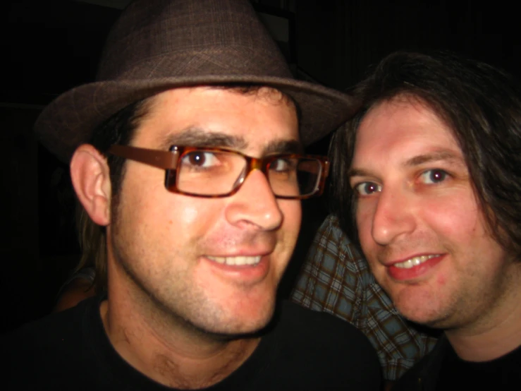 man wearing glasses and a hat posing for a po with another man