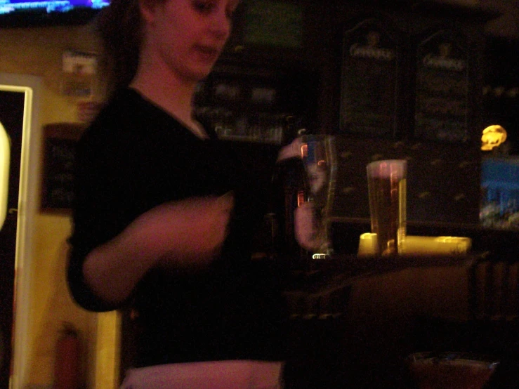 a woman standing next to the counter holding a glass of beer