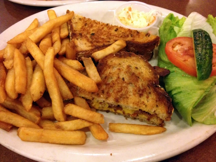 the plate is full of fries, a salad and a sandwich