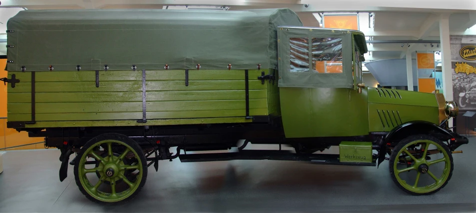 an old green and black truck inside of a building