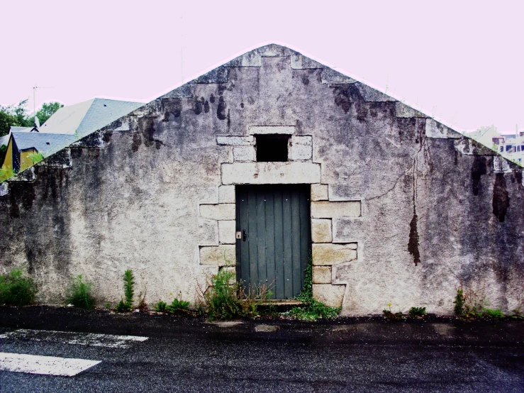 a gray wall with an open window near a small door