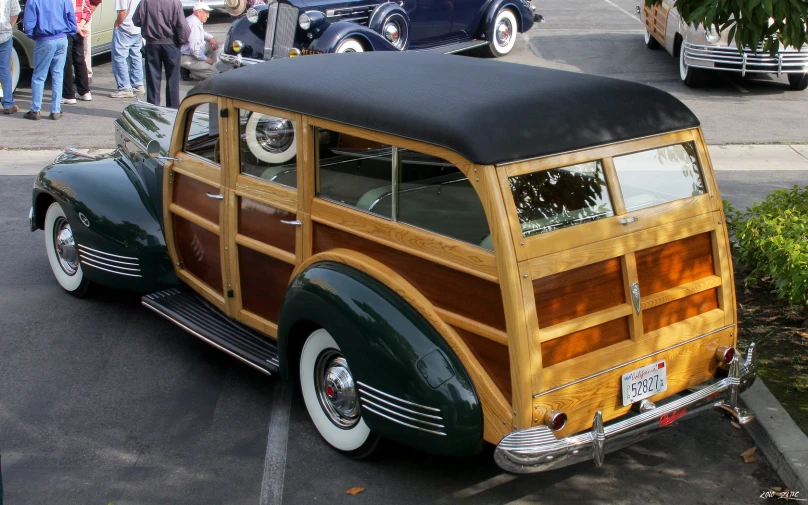 an old style woodie station wagon sits in a parking lot
