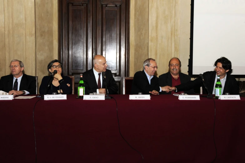 five men sitting at a table with glasses and bottles