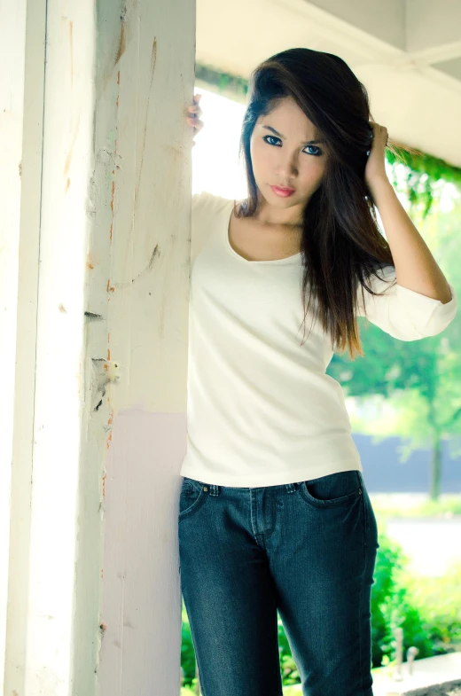 a woman is leaning against the side of a pillar