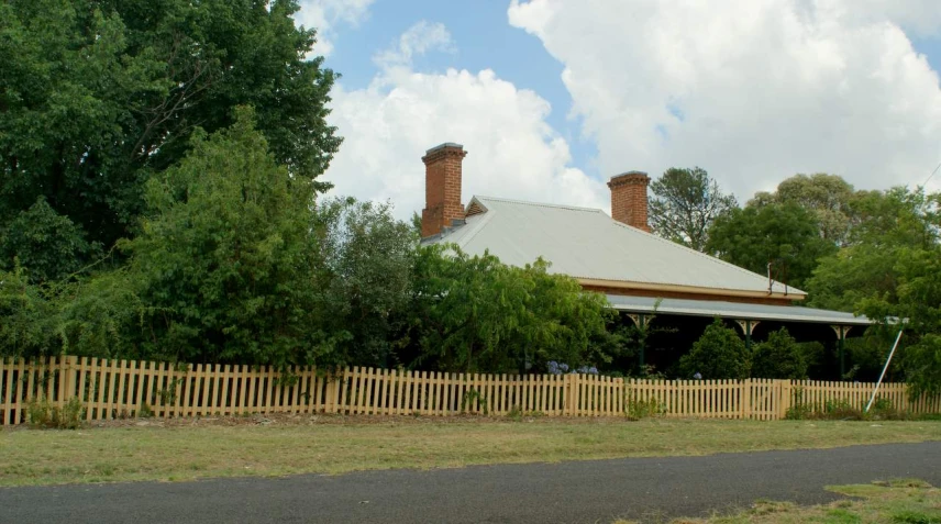 two chimneys on top of a house near a fence