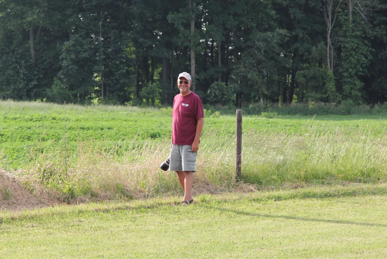 the man stands near a wooden post in the field