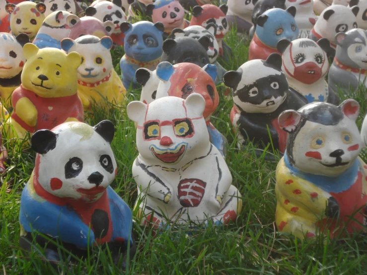 several toys in the shape of a panda, panda bear, dog, pig and snake are arranged together on grass