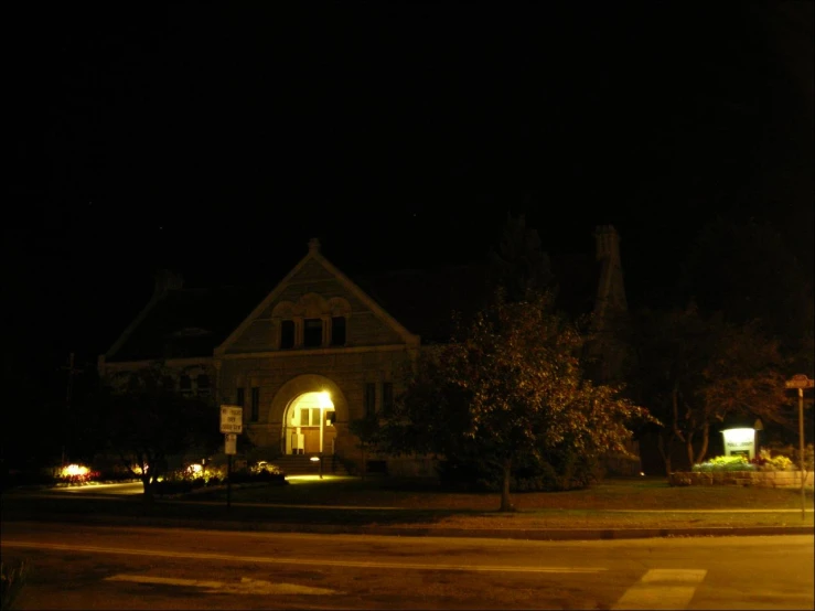 a church building in the dark with cars driving on the street