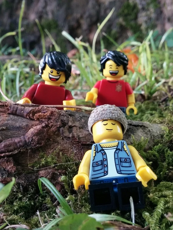 three legos are standing together next to a tree stump