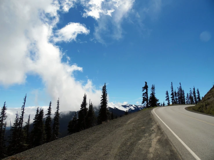 road winding on a sunny day with clouds coming off of top