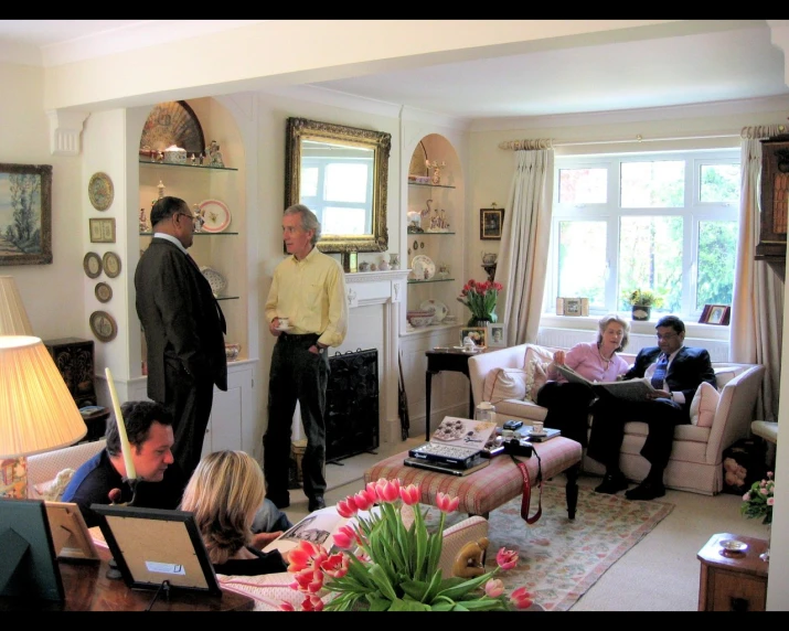 a living room with several people and a man standing in the middle