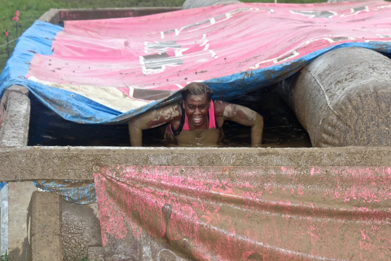 a woman sits under a large buliding made from plastic bags