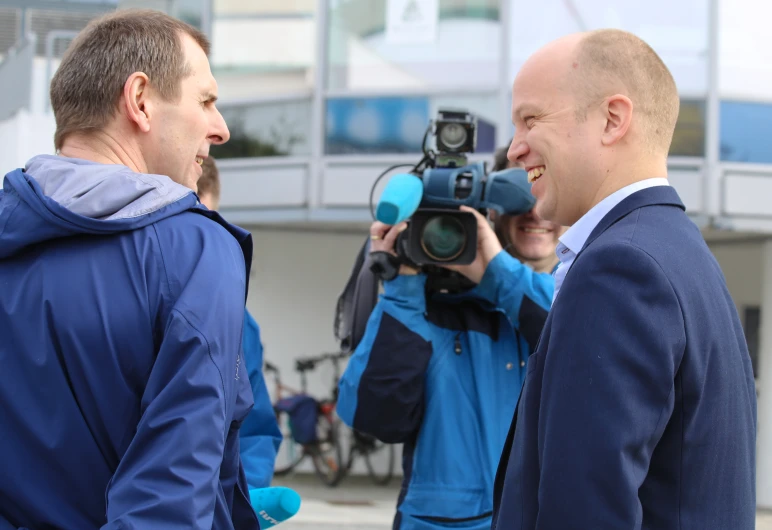 two men in business suits are sharing a laugh