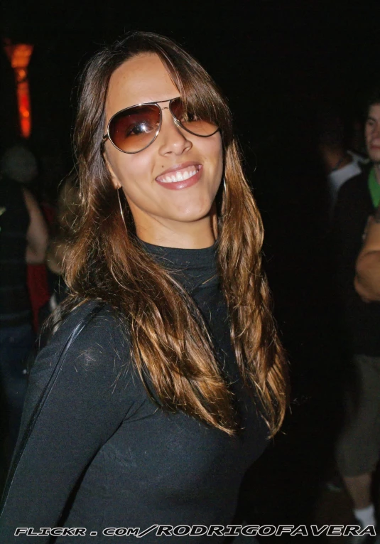 a woman wearing sunglasses with a crowd in the background