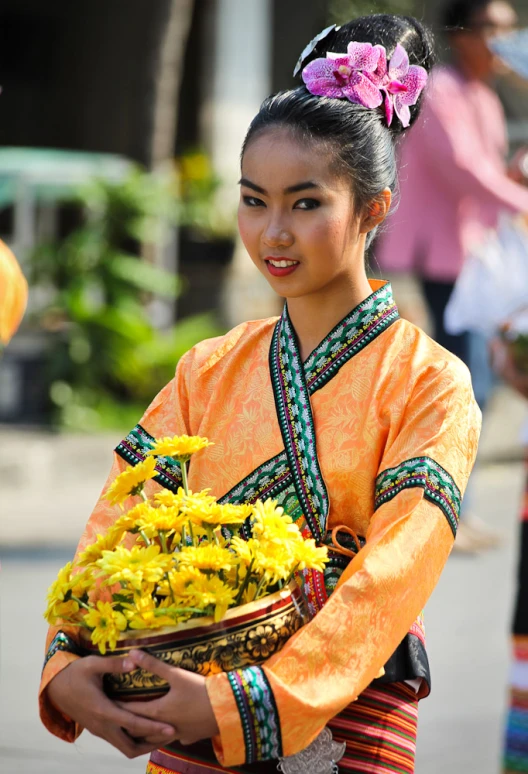 an asian woman holding baskets of yellow flowers