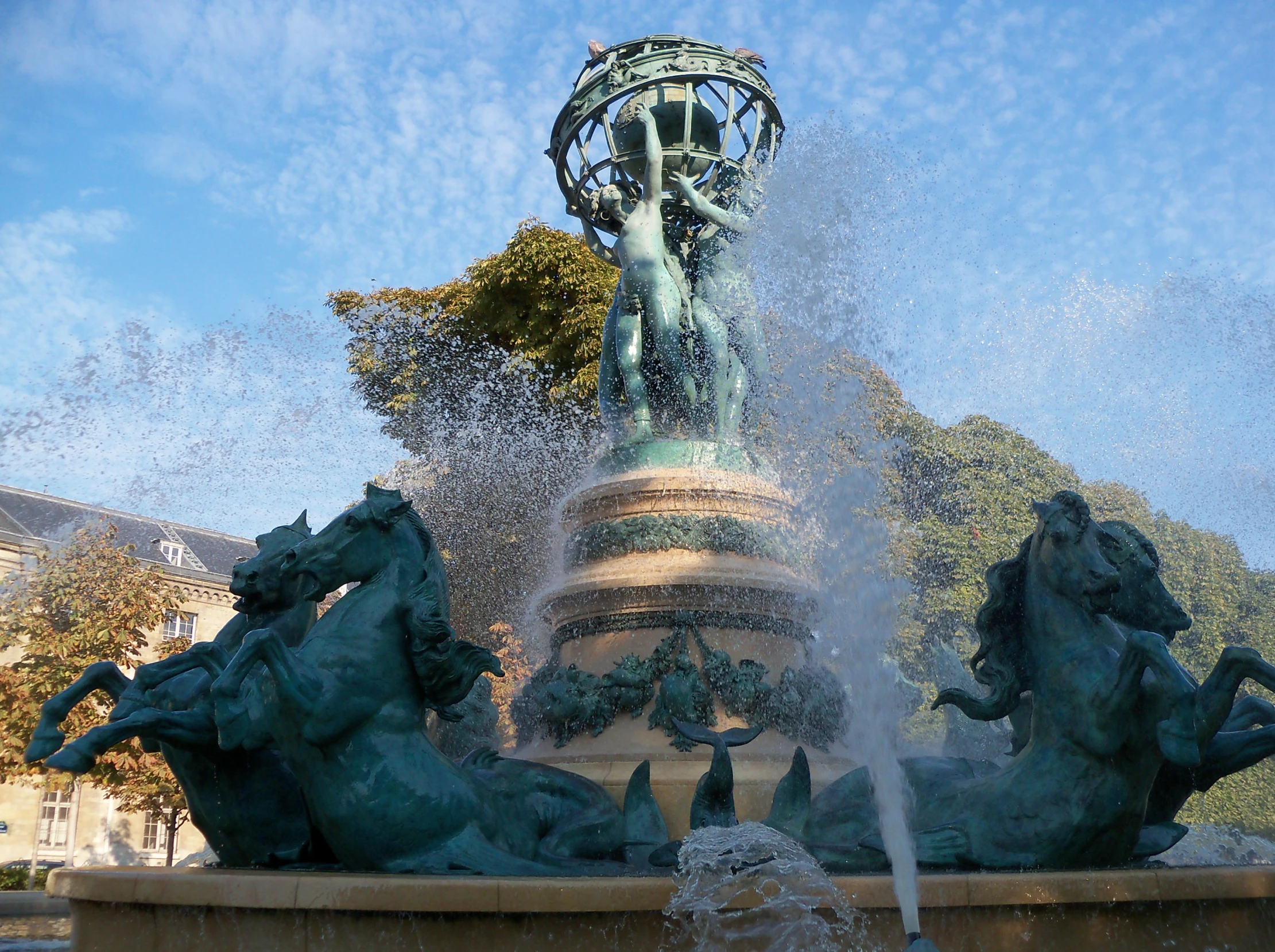 a large fountain next to a small statue