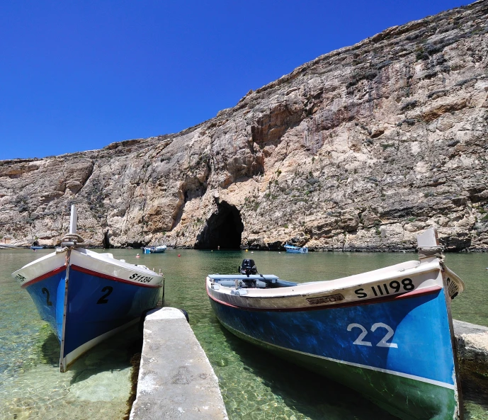 two boats docked near an area with very rocky cliffs in the background