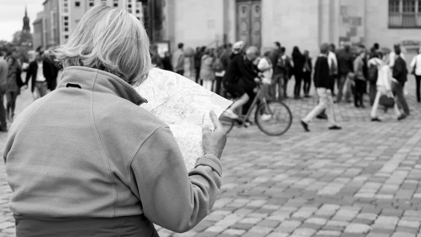 a woman holds up a map on a city street