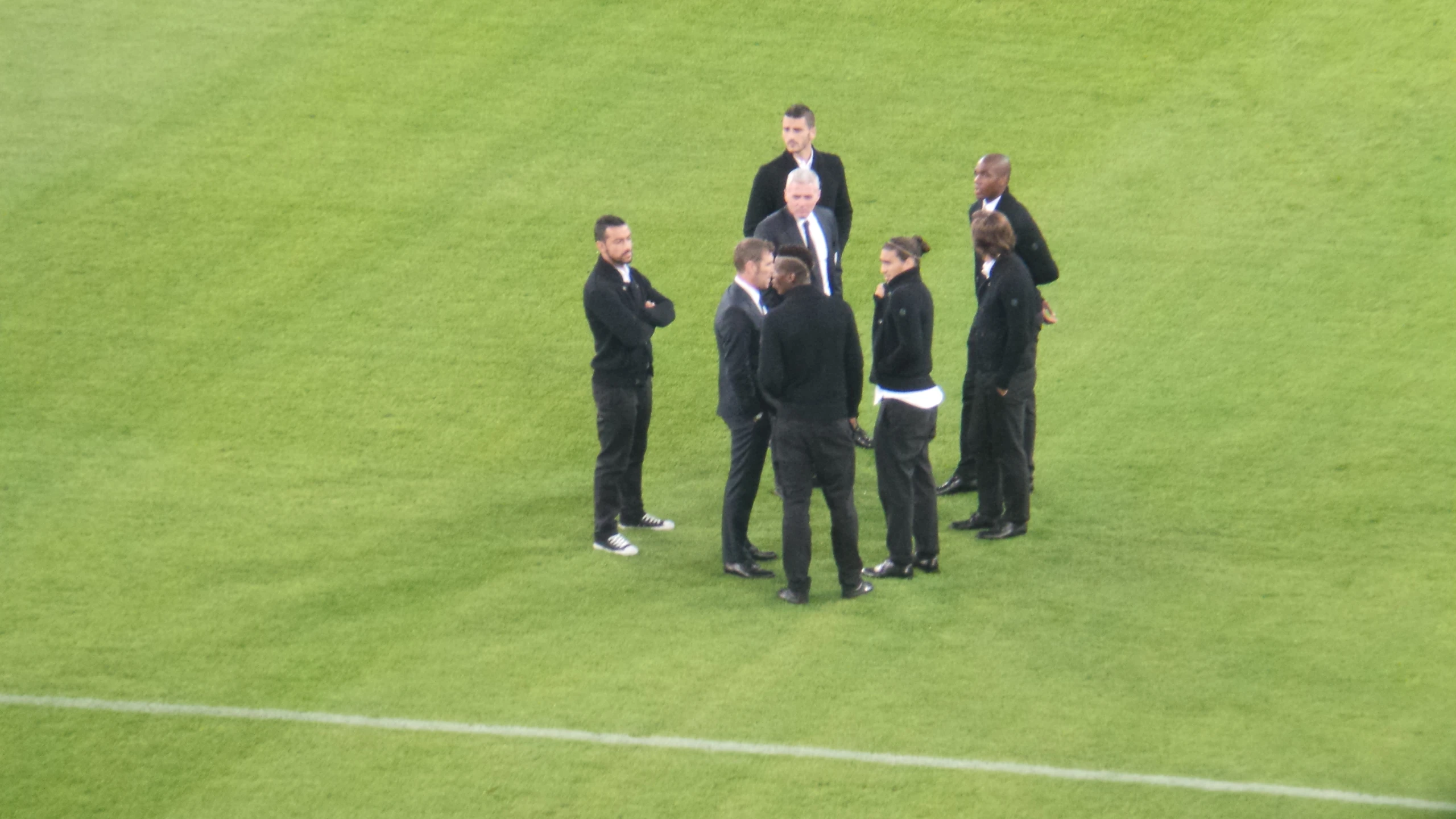 a group of men standing around on top of a soccer field