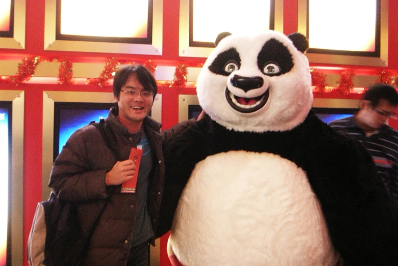 a man standing next to a giant panda mascot