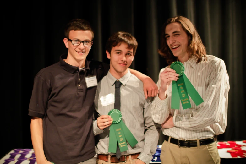 three young men standing next to each other holding green ribbons
