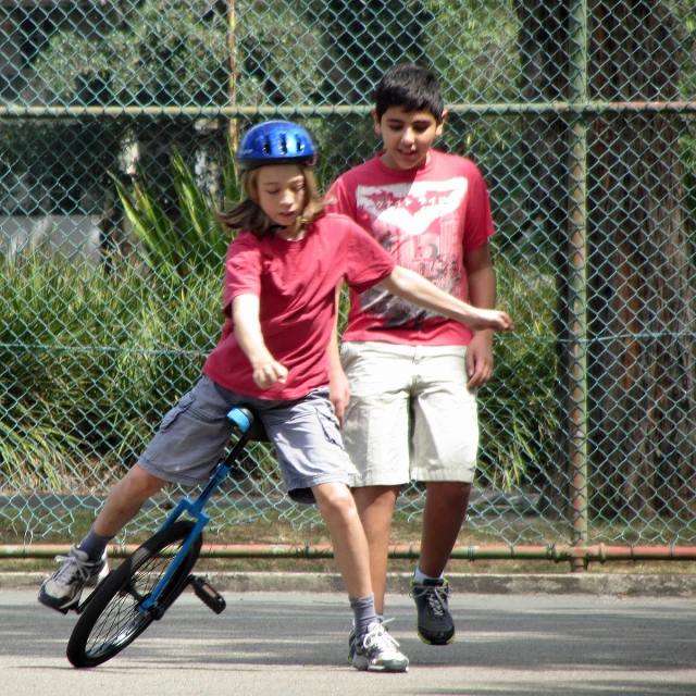 two boys on skateboards on street with fence