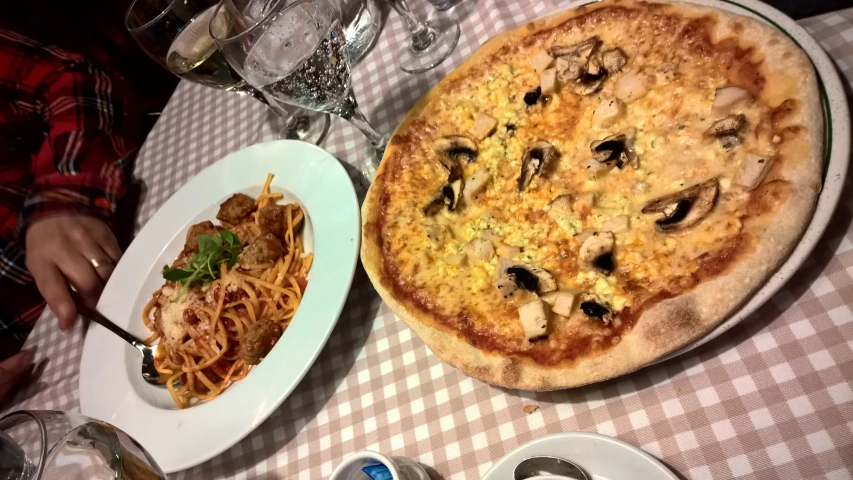 some plates and glasses on a table with a pizza