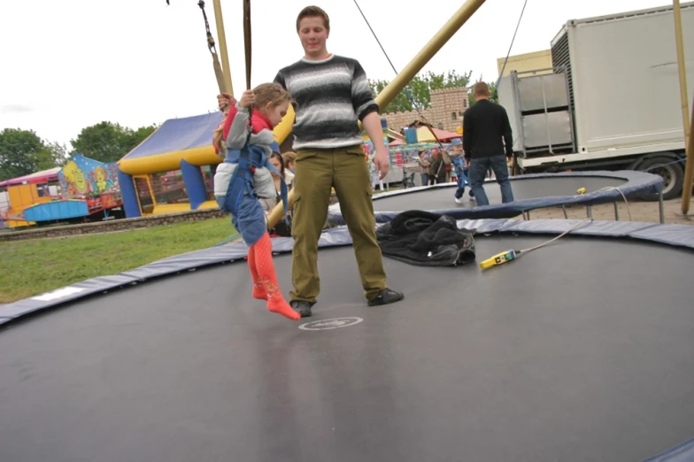 a man is walking on a trampoline with two children