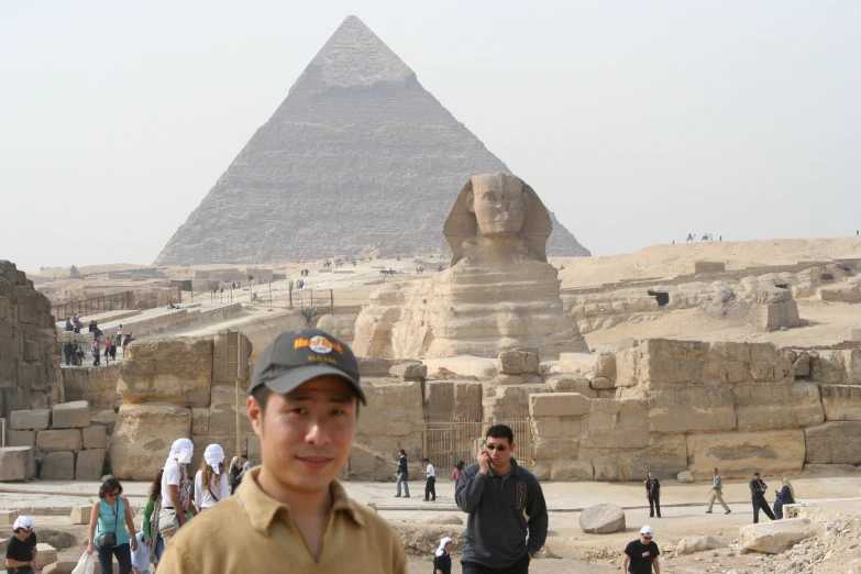 a man stands near the pyramids while another person looks on