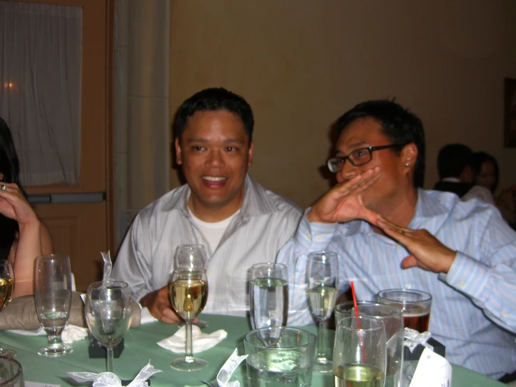 three men are sitting at a dinner table